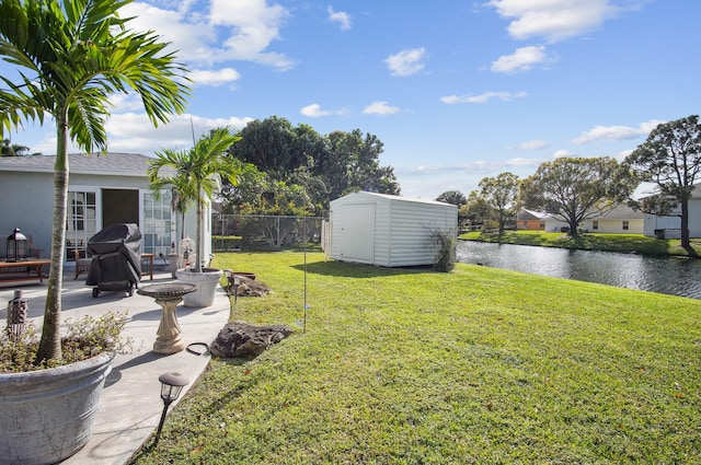 view of yard featuring a patio area, a storage unit, and a water view