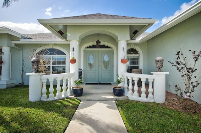 view of exterior entry featuring a lawn and a porch