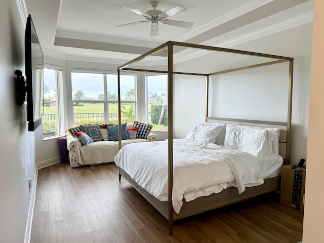 bedroom featuring ceiling fan, dark wood-type flooring, ornamental molding, and a raised ceiling