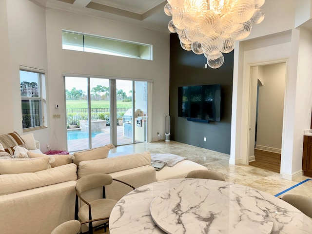 living room with a notable chandelier, light hardwood / wood-style floors, a towering ceiling, crown molding, and french doors