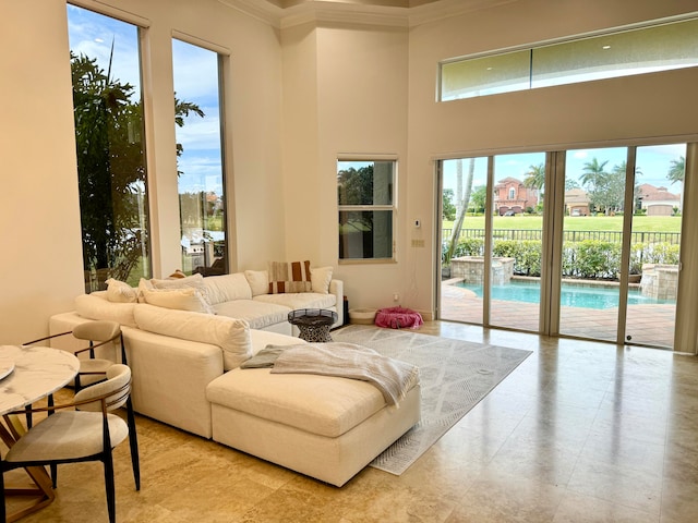 living room featuring crown molding, light tile flooring, and a towering ceiling