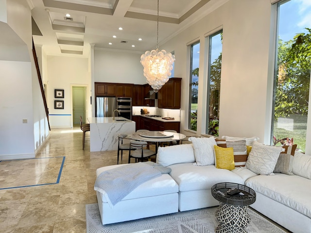 living room with an inviting chandelier, coffered ceiling, light tile floors, ornamental molding, and a high ceiling