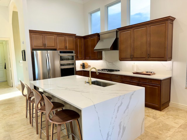 kitchen with custom range hood, appliances with stainless steel finishes, sink, light stone countertops, and tasteful backsplash