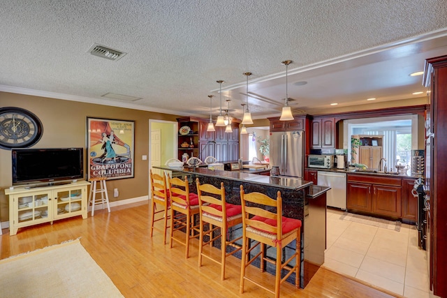 kitchen featuring appliances with stainless steel finishes, a kitchen bar, a kitchen island, and light hardwood / wood-style floors