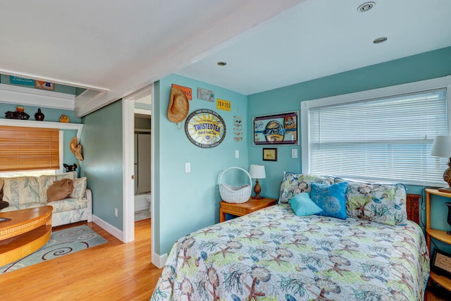 bedroom with beam ceiling and hardwood / wood-style flooring