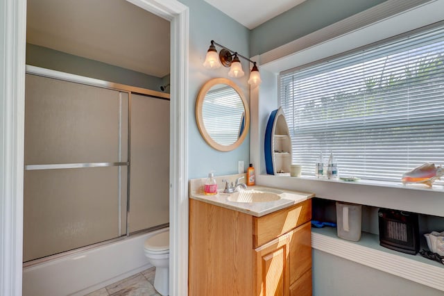 full bathroom with vanity, bath / shower combo with glass door, toilet, and tile patterned flooring