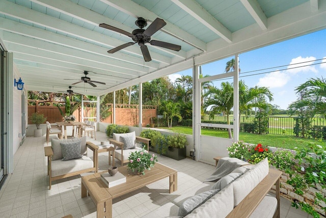 sunroom with ceiling fan and beamed ceiling