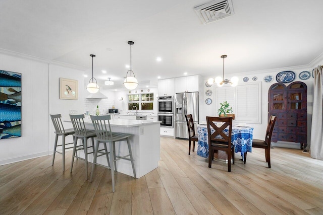 kitchen featuring decorative light fixtures, white cabinets, sink, and appliances with stainless steel finishes