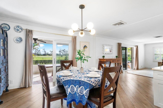 dining room with an inviting chandelier, light hardwood / wood-style floors, and crown molding