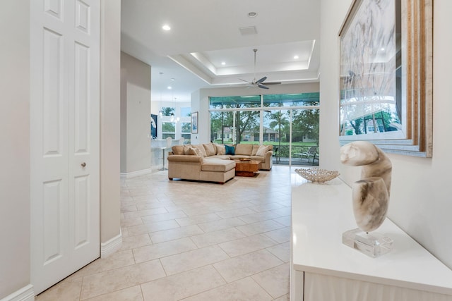 tiled living room featuring a raised ceiling and ceiling fan