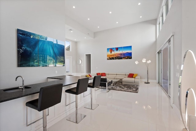 dining area featuring sink, light tile floors, and a towering ceiling