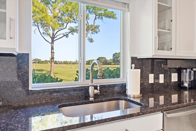 kitchen featuring white cabinetry, sink, dark stone countertops, dishwasher, and tasteful backsplash