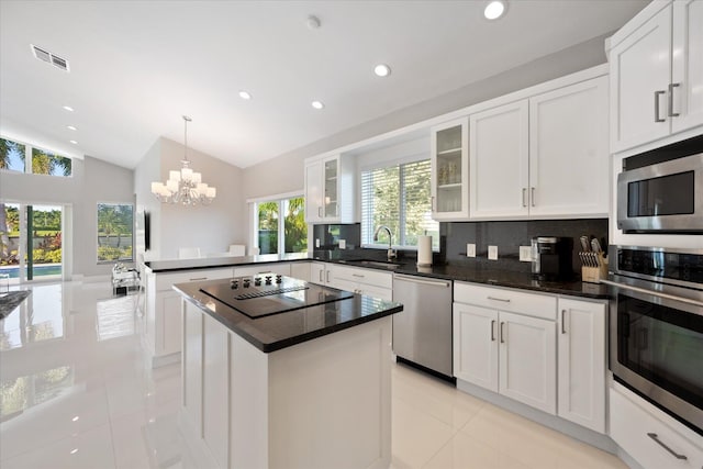 kitchen with backsplash, stainless steel appliances, light tile flooring, a notable chandelier, and a center island