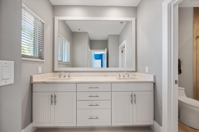 bathroom with dual vanity and toilet