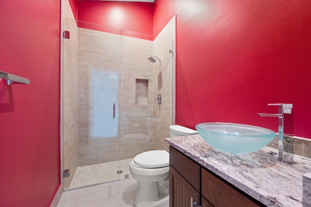 bathroom with toilet, vanity, and a shower with shower door