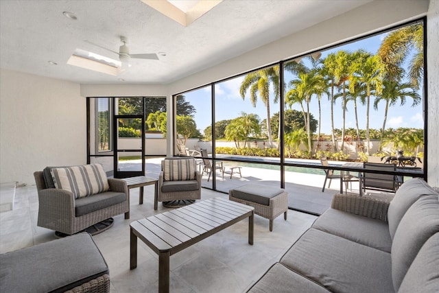 living room with a skylight, ceiling fan, a textured ceiling, and a wealth of natural light