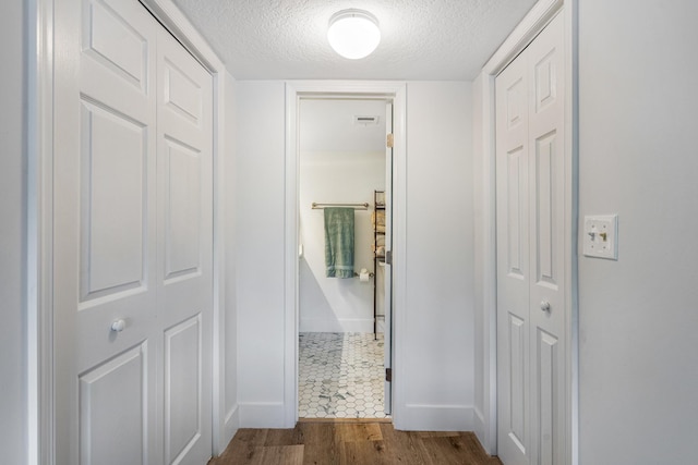 corridor with a textured ceiling and dark tile flooring