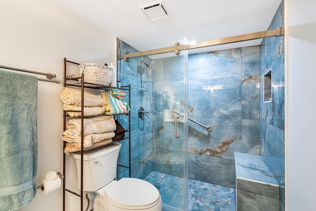 bathroom featuring toilet and a shower with shower door