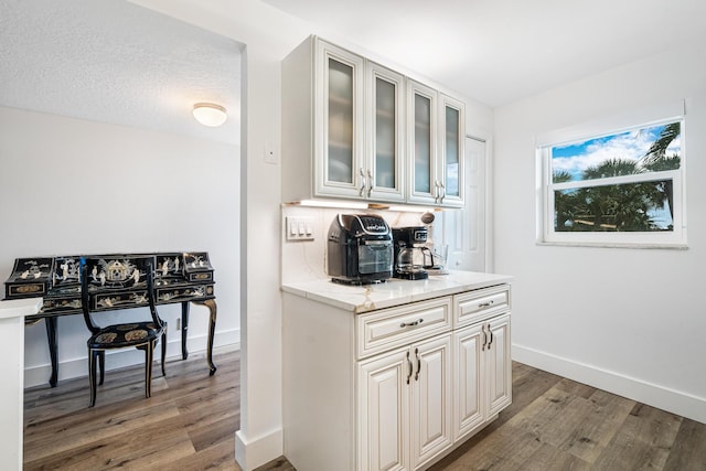 kitchen featuring a textured ceiling, dark wood-type flooring, white cabinetry, and light stone counters