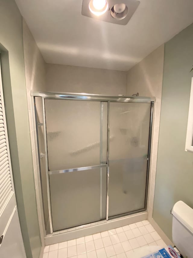 bathroom featuring tile patterned floors, walk in shower, and toilet