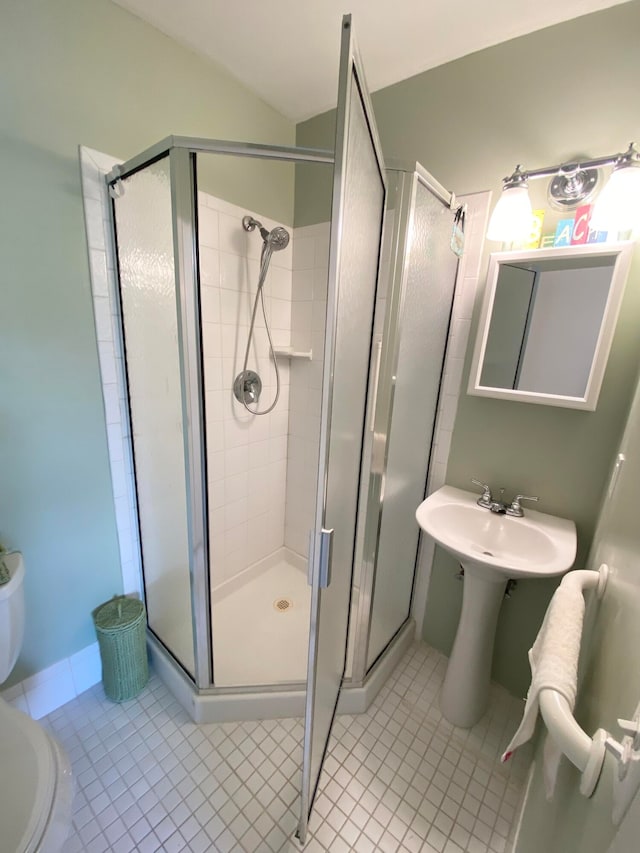 bathroom featuring toilet, tile patterned floors, an enclosed shower, and sink