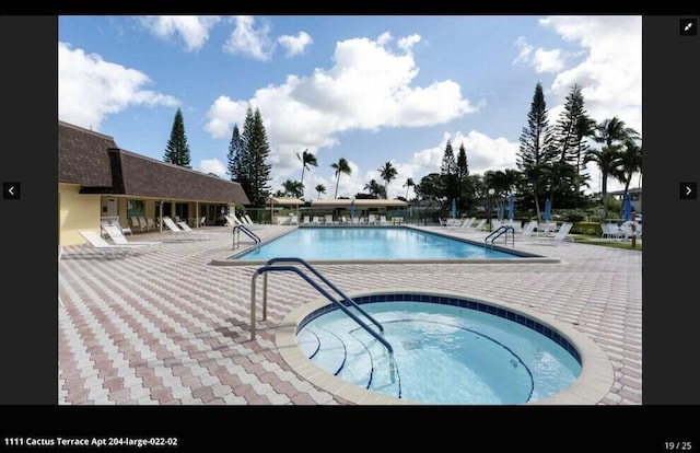 view of swimming pool featuring a patio and a hot tub