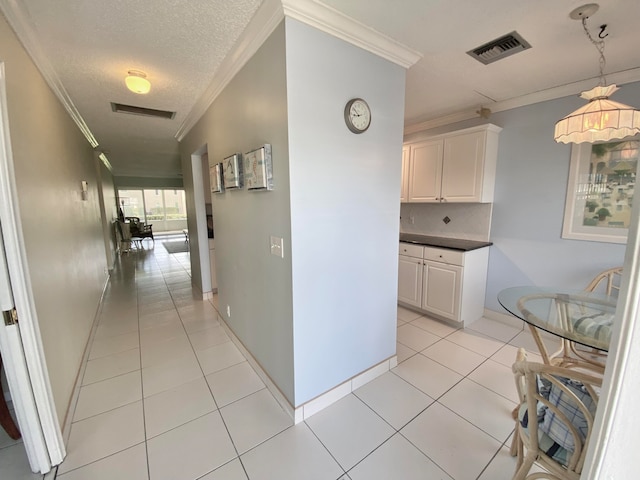 corridor with crown molding, light tile patterned flooring, and a textured ceiling