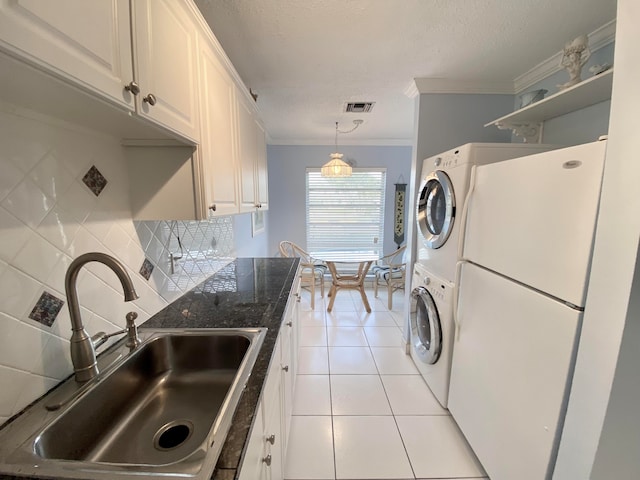 laundry room with light tile patterned floors, ornamental molding, stacked washer / drying machine, and sink