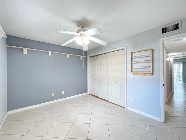 unfurnished bedroom featuring light tile flooring, a closet, and ceiling fan