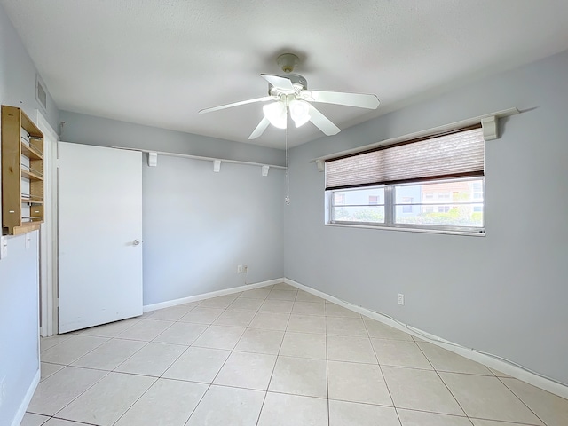 spare room featuring light tile floors and ceiling fan