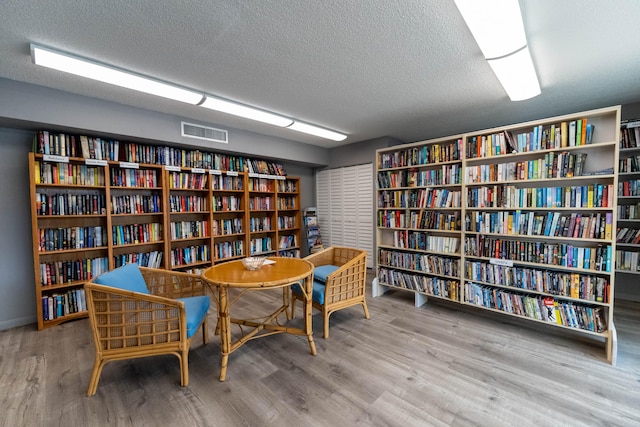 living area with a textured ceiling and light wood-type flooring