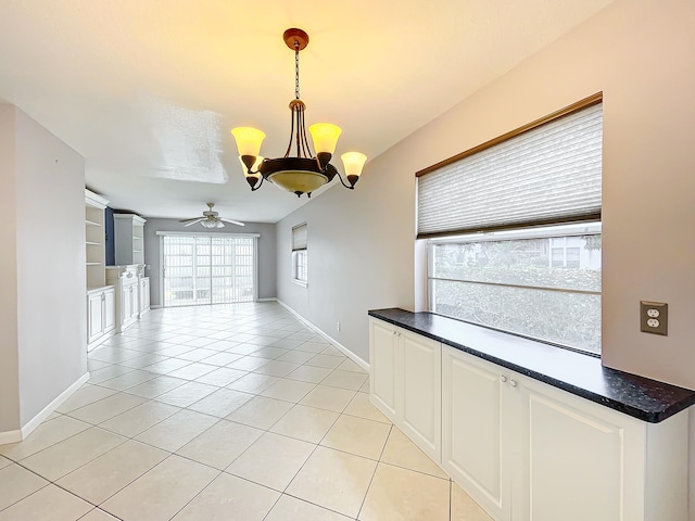 interior space featuring light tile floors and ceiling fan with notable chandelier