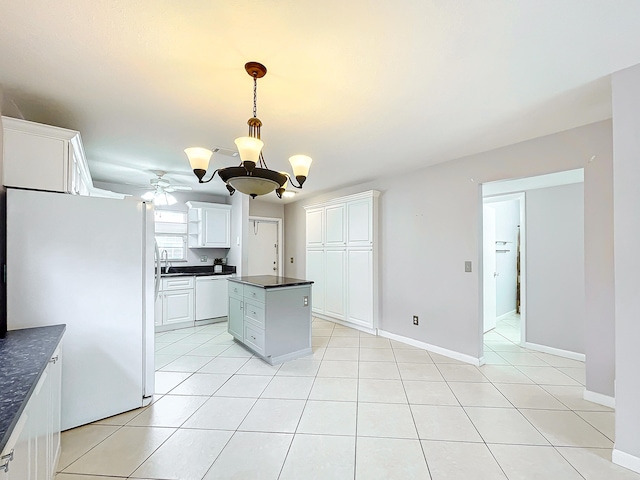 kitchen featuring white cabinetry, ceiling fan with notable chandelier, light tile flooring, white appliances, and a center island