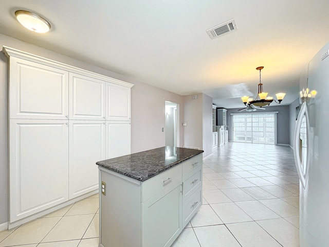 kitchen with white refrigerator, a kitchen island, white cabinets, decorative light fixtures, and ceiling fan with notable chandelier