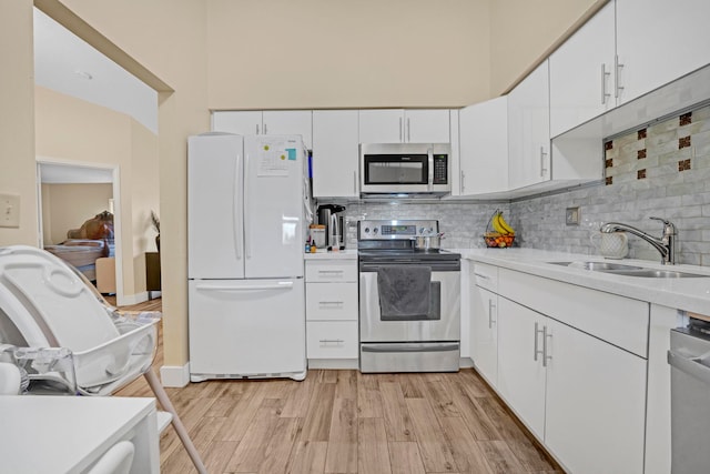 kitchen with sink, appliances with stainless steel finishes, decorative backsplash, and light hardwood / wood-style floors