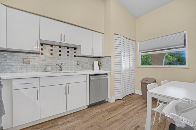 kitchen with light hardwood / wood-style flooring, sink, backsplash, white cabinetry, and dishwasher