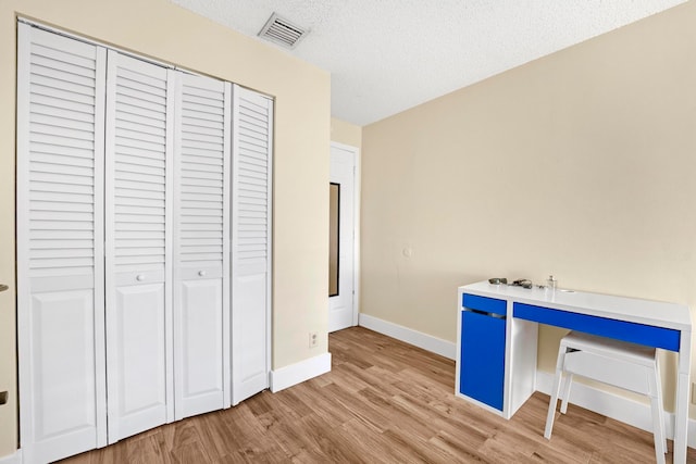 unfurnished office with light wood-type flooring and a textured ceiling