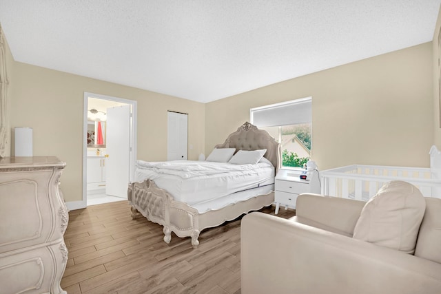 bedroom featuring ensuite bathroom and light wood-type flooring