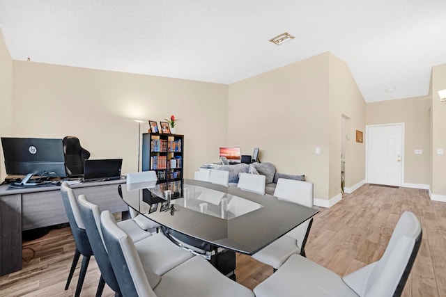 dining room featuring light hardwood / wood-style floors and vaulted ceiling