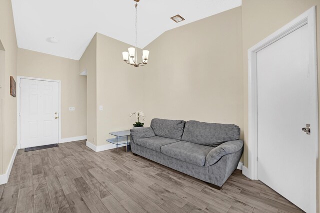 living room with hardwood / wood-style flooring, lofted ceiling, and a chandelier