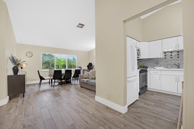 kitchen with stove, light wood-type flooring, tasteful backsplash, and white cabinets