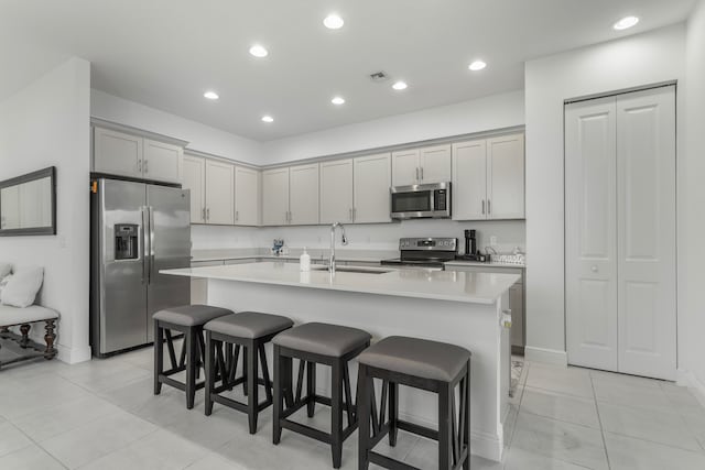 kitchen with sink, appliances with stainless steel finishes, a breakfast bar area, and a center island with sink