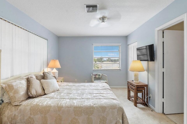 bedroom featuring light colored carpet, a textured ceiling, and a closet