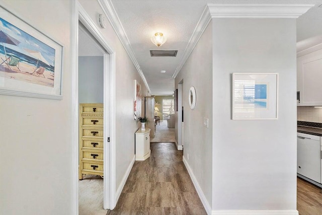 corridor with a textured ceiling, light hardwood / wood-style floors, and crown molding