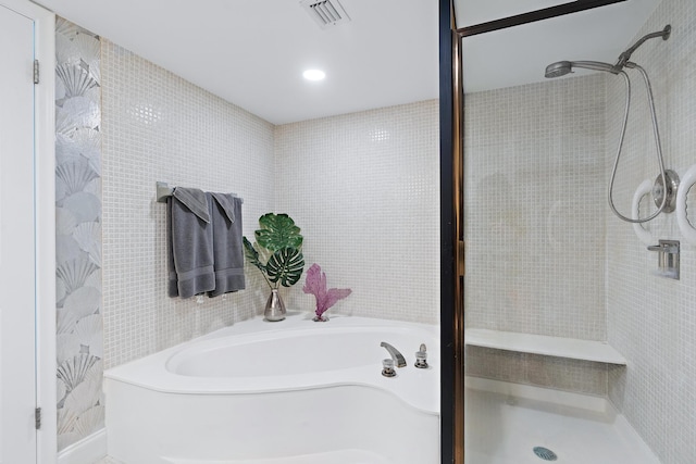 bathroom featuring plus walk in shower and tile walls