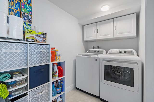 laundry room with cabinets, washing machine and dryer, and light tile patterned floors