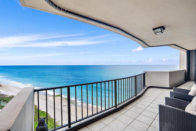 balcony featuring a water view and a beach view