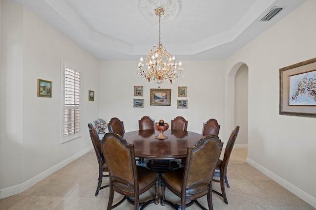 dining room featuring light tile flooring, a raised ceiling, and a chandelier