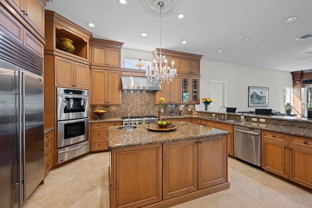 kitchen featuring backsplash, wall chimney range hood, stainless steel appliances, light tile floors, and dark stone counters