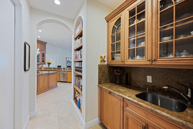 kitchen with sink, dishwasher, light tile flooring, tasteful backsplash, and dark stone countertops